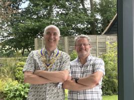 Incoming president Howard on the left and past president Mike on the right both with arms folded standing in a garden.